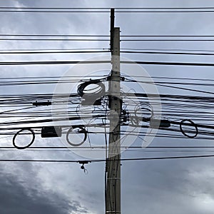 Power cables and communication lines on electric pole against sky
