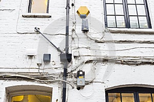 Power cables, communications and alarm on an old white wall