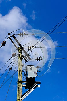 High voltage electrical power cables and transformer seen erected on a wooden pole.