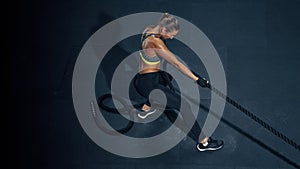 Power caucaian woman functional training with black rope at a gym. Copy free space on left