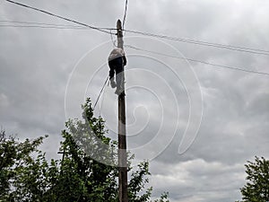 Power electrician lineman at work on pole against the gloomy sky