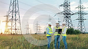 Power engineers are talking near electrical transmission towers