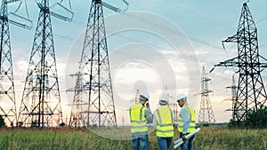 Power engineers are walking along the field with electrical towers