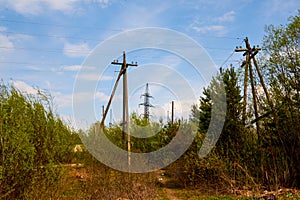 Power line support. Rustic wooden Telegraph pole full length against a blue sky with clouds. Electric pole with wires in