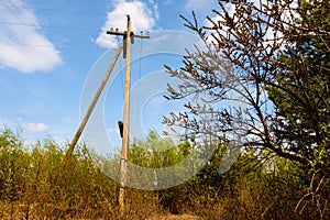 Power line support. Rustic wooden Telegraph pole full length against a blue sky with clouds. Electric pole with wires in