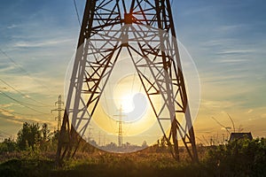 Power line support tower and sunset sun