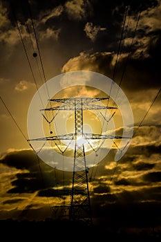 A power line tower is silhouetted against a cloudy sky