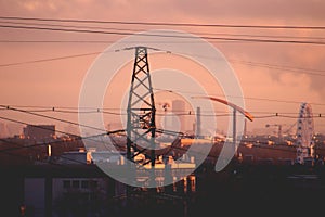 Power line tower with wires against industrial city skyline