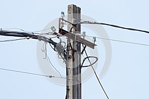 Power line on a wooden post against the blue sky