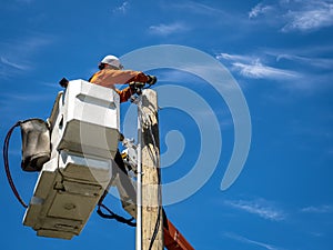 Power lineman at work in an aerial bucket connecting a new house service on a summers day