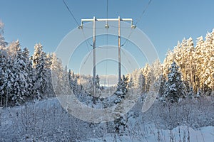 Power lines cross the countryside in a snowy and sunny sweden