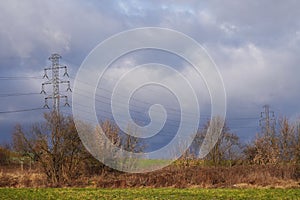 Power lines in the field against the background of a bright sky