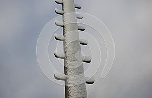 Power lines frozen by a large layer of ice layer in the shape of a cylinder with icicles. icing burdens the poles, ladder and ligh