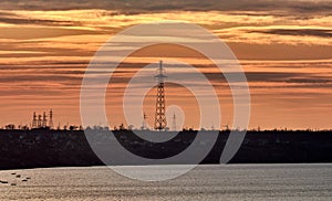 Power lines on an island in the sea against the backdrop of a yellow-orange multicolored sunset