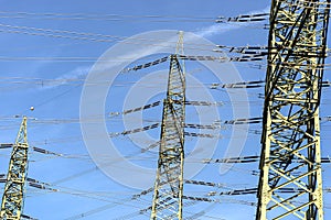 Power lines and pylons for transmission of electricity, against a blue sky background.