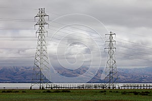 Power Lines with scenic marsh, bay, mountain range, and cloudy skies