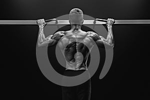 Power muscular bodybuilder guy doing pullups in gym. Fitness man photo