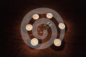 Power outage concept. Non-burning electric light bulb in a circle of burning candles
