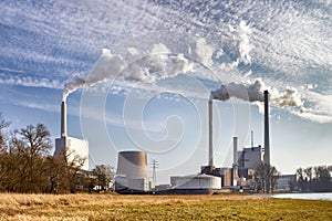 Power plant with chimneys and smoke under blue sky