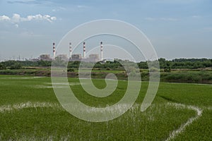 Power plant with green field againts sky