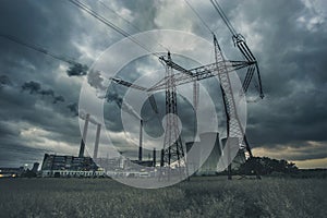 Power plant with high voltage power line and dramatic clouds.