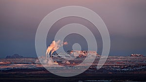 Smoking industrial chimneys in red desert in sunset.