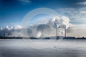 Power plant smokes in blue dramatic sky in a winter city. Free copyspace text