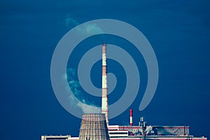 Power plant with two smoking chimney in front of blue sky. Cooling tower of power-plant against the blue sky