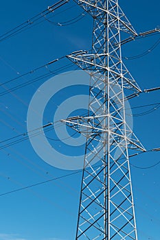 Power pole for electricity transmission and distribution in front of blue sky