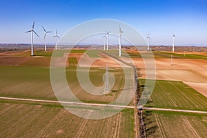 A power pole and many huge wind turbines on a field seen from above as a drone shot, Energiewende, Germany