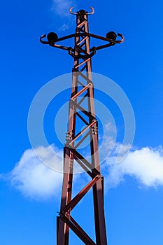 A power pole of vintage design against a blue sky