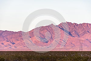 Power pylons in mountainous desert landscape at sunset, Mojave Desert, California, USA