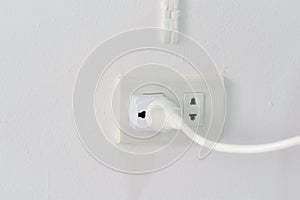 Power saving concept, plug on the electric socket on white wall.