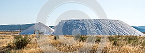 Power shovel machinery in front of two large mountains of salt