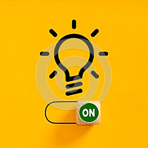 Power on slider button under a light bulb idea symbol on yellow background. Process of finding a creative idea