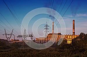 Power station with smoking chimney among electric wires