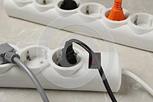 Power strip with extension cords on grey marble table, closeup. Electrician\'s equipment