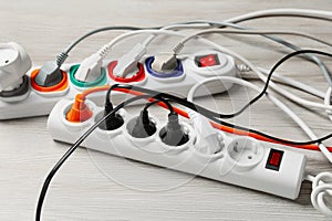 Power strip with extension cords on white wooden floor. Electrician\'s equipment