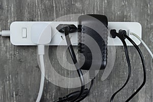 Power strip with multiple electrical cords plugged in on gray background