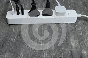 Power strip with multiple electrical cords plugged in on gray background. Space for text