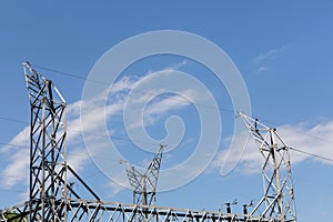 Power substation electrical trusses, metal structures with wires against a blue sky with clouds