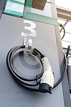 Power supply connecter to plug-in electric vehicle or electric car at charging station in car park area of shopping plaza