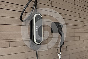 Power supply for hybrid electric car charging battery on wall brick background. Eco-car concept