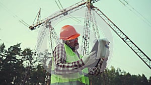 Power systems engineer on site. An engineer worker is talking on a mobile phone and checking the data in documents
