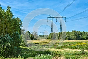 Power transmission line support against the background of a field and forest