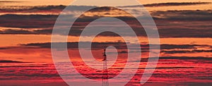 Power transmission lines against the background of a red-orange multicolor sunset