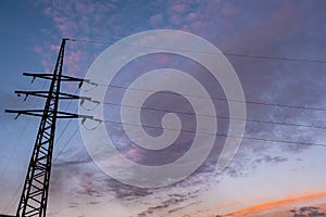 Power transmission pylon against the sky with orange and dark clouds