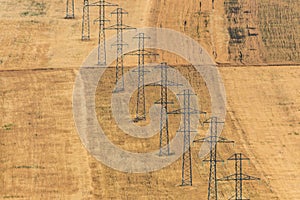 Power transmission towers in the yellow farm field