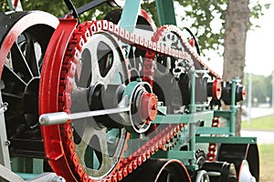 Power unit with wheels, flywheels and chain. Agricultural mechanism for harvest processing. Heavy engineering. Metal construction.