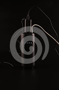 powerbank black on a black background, usb cables, plug, light and reflection